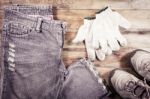 Jeans And Sneakers With Gloves On A Wood Background Stock Photo