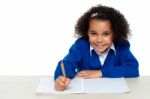 Cute Primary Kid Writing Her Assignment Stock Photo