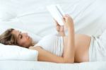 Pregnant Woman Reading A Book On Sofa Stock Photo