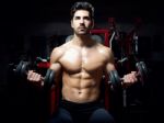 Young Man Doing Heavy Weight Exercise In Gym Stock Photo