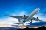 Commercial Airplane Flying At Sunset Stock Photo