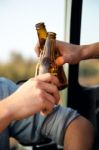 Portrait Of Two Friends Toasting With Bottles Of Beer In Car Stock Photo