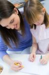 Child Drawing With Crayons With Her Mom At Home Stock Photo