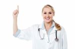 Smiling Female Doctor Pointing Upwards Stock Photo