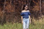 Portrait Of Beautiful Young Asian Woman Standing Against Dry Plant On Grass Field Stock Photo