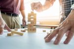 Hand Of Engineer Playing A Blocks Wood Tower Game (jenga) On Blu Stock Photo