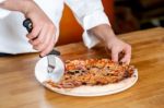 Chef Cutting Pizza With Cutter Stock Photo