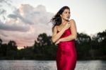 Beautiful Young Woman In The Gardens Wearing A Long Silk Red Dress Stock Photo