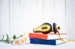 Headphones On Books With Flowers On White Wood Background Stock Photo