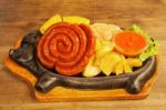 Sausage With Potatoes, Vegetables And Hot Sauce On A Plate Stock Photo