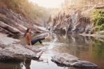 Young Woman On A River Bank Playing With Water Stock Photo