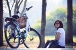 Asian Woman Sitting In The Park With Bicycle In Morning Stock Photo