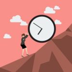 Business Woman Pushing Huge Clock Uphill Stock Photo