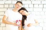 Young Pregnant Woman And Her Husband With Red Alarm Clock Stock Photo