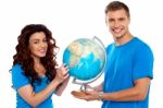 Smiling Young Couple Holding Globe Stock Photo