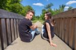 Young Attractive Dutch Couple Sitting On Wooden Bridge Stock Photo