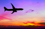 Silhouetted Commercial Airplane Flying At Sunset Stock Photo