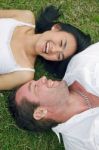 Couple Lying On Lawn Stock Photo