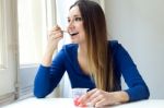 Young Beautiful Woman Eating Yogurt At Home Stock Photo