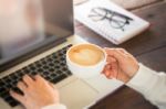 Hand On Cup Of Coffee At Work Table Stock Photo