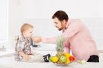 Father Feeding Child In Kitchen Stock Photo