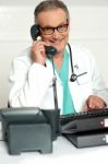 Senior Doctor Talking Over Phone Stock Photo