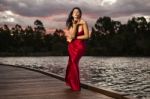 Beautiful Young Woman In The Gardens Wearing A Long Silk Red Dress Stock Photo