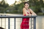 Beautiful Young Woman In The Gardens Wearing A Long Silk Red Dress Stock Photo