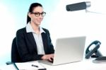 Smiling Female Secretary Working On Laptop Stock Photo