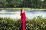 Beautiful Young Woman In The Gardens Wearing A Long Silk Red Dress Stock Photo