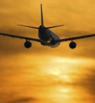 Airplane Flying Towards Sunset Stock Photo