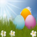 Colorful Easter Eggs Sitting On Grass Field With Blue Sky Background Stock Photo