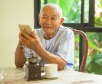 Happy Asian Senior Man Using The Mobile Phone In Home Stock Photo