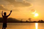 Arms Raised Man Watching Sunset Stock Photo