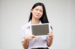 Portrait Of Thai High School Student Uniform Beautiful Girl Using Her Tablet Stock Photo