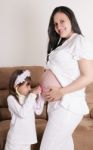 Girl Examining Pregnant Mother's Tummy Stock Photo