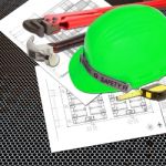 Green Helmet Of Safety Officer Constructor With Blueprints Stock Photo