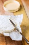 Camembert Cheese Wrapped In Paper With Vintage Knife On Wooden T Stock Photo