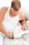 Man Lying On Bed And Reading Book Stock Photo