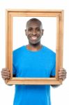 Smiling Guy Looking Through Picture Frame Stock Photo