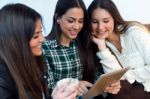 Three Young Woman Using Digital Tablet At Cafe Shop Stock Photo