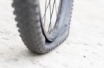 Bicycle Wheel With Flat Tyre On The Concrete Road Stock Photo