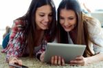 Two Beautiful Young Woman Friends Using Digital Tablet At Home Stock Photo