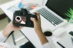 Photographer Holding Camera Checking Photo On Her Desk Workspace Stock Photo