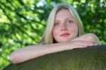 Blonde Girl Leaning On Branch In Nature Stock Photo