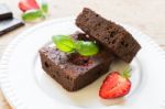 Chocolate Brownie Cake On White Plate Decorated With Strawberrie Stock Photo