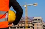 Young Engineer Wearing A Orange Shirt Stands Holding A Hat While Stock Photo