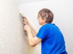 Worker In Protective Gloves With Spatula Smoothing Wallpaper Stock Photo