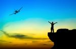 Silhouette Of A Man On The Rock And Silhouette Commercial Plane Stock Photo