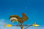 A Cockerel Wind Vane Against Blue Sky Stock Photo